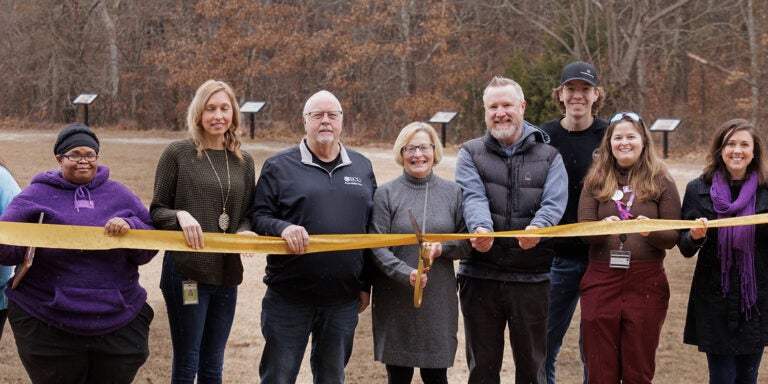 Group of people performing ribbon-cutting with large scissors at Wildwood Park.