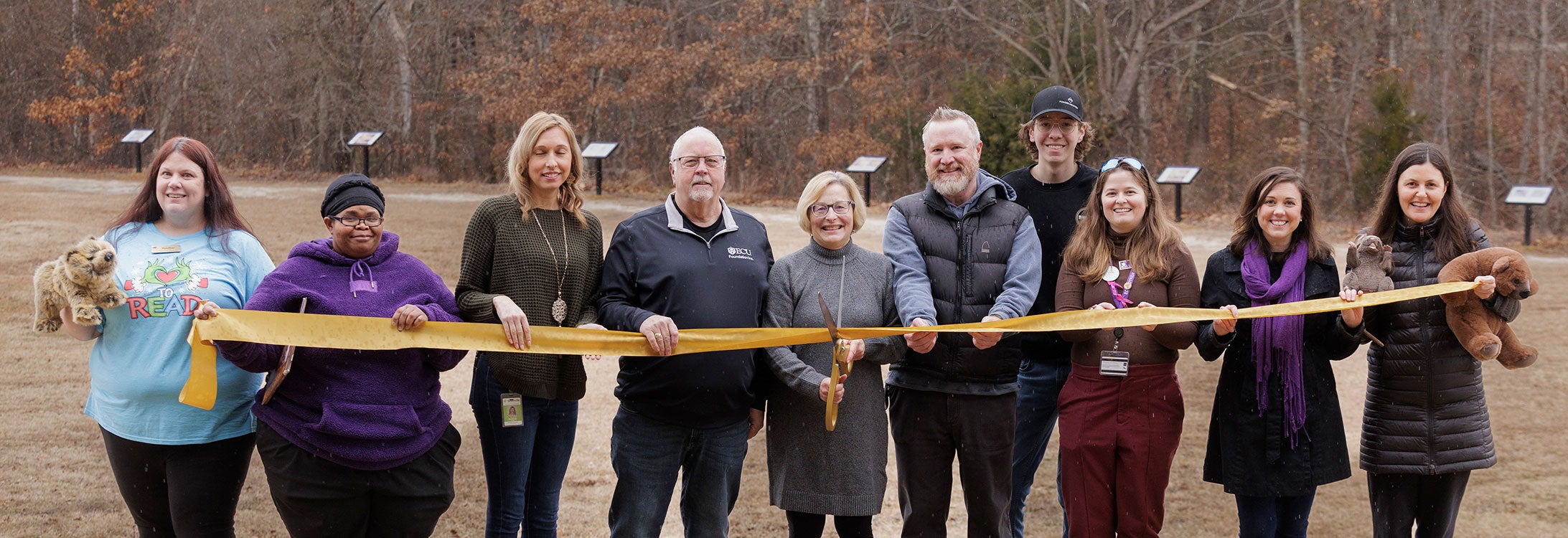 Group of people performing ribbon-cutting with large scissors at Wildwood Park.