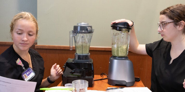 Two women separate food into bowls in a well-lit indoor space.