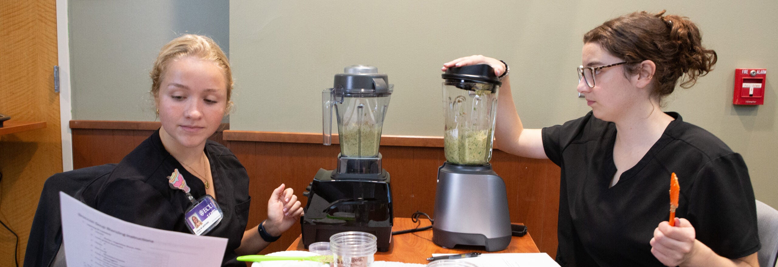 Two women separate food into bowls in a well-lit indoor space.