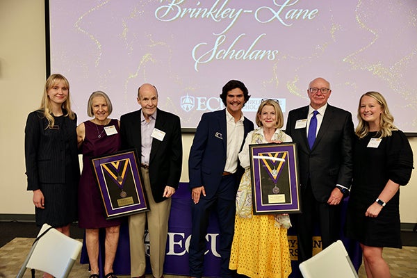 Agne Shields, left, Toby Bryson, center, and Abby Ulfers, right, present Lynn and Pat Lane and Amy and Robert Brinkley with framed Brinkley-Lane medallions.