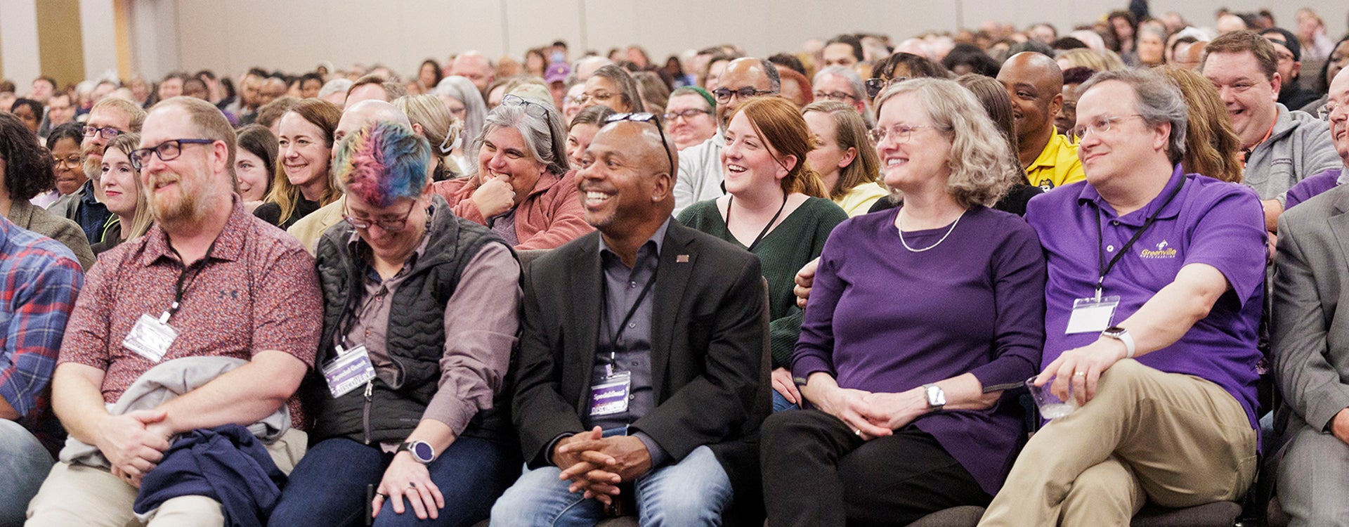 A room full of spectators in business casual sitting close together on chairs in ECU’s Main Campus Student Center ballroom as they smile and laugh while listening to LeVar Burton.