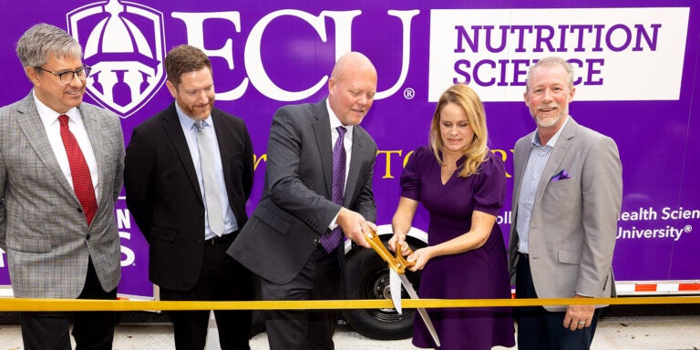 Food Lion representatives Kevin Durkee, David Hardee and David Garris join ECU nutrition science faculty Dr. Lauren Sastre and department chair Dr. Michael Wheeler in cutting the ribbon to open the ECU/Food Lion Feeds mobile teaching kitchen and pantry. (ECU Photo by Rhett Butler)
