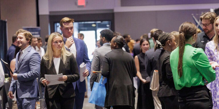 A large group of college students dressed in business attire mingle at a career fair.