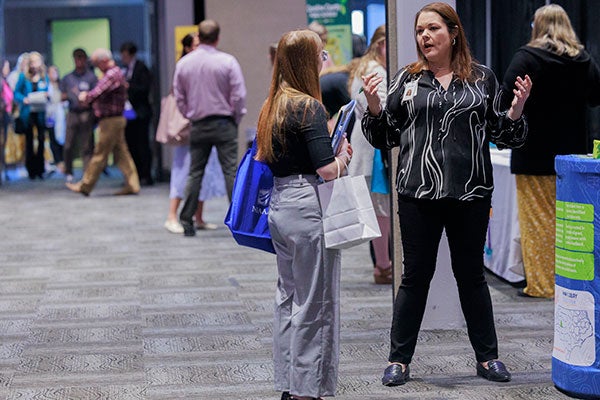 An ECU student speaks to a female representative in front of a career fair booth.