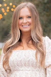 A woman with long blond hair poses for a photo.