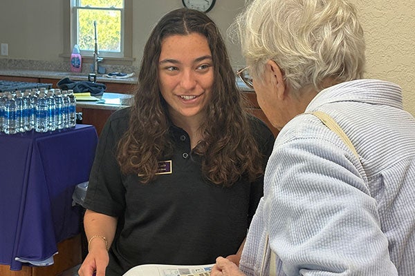 An East Carolina University student holds a clipboard with data and speaks to a woman from Dare County.