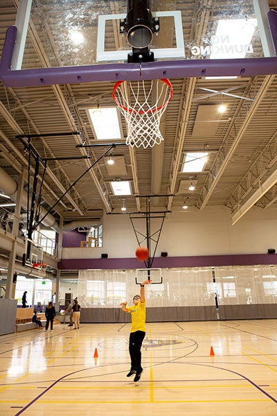 A boy in a yellow T-shirt plays basketball.