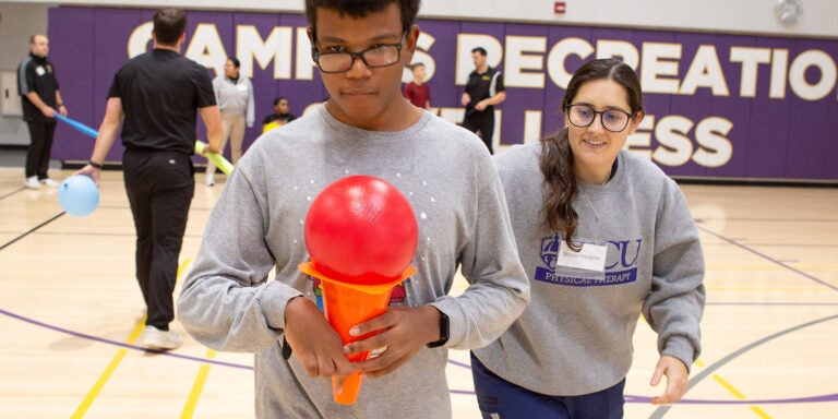 A physical therapy student encourages a HABIT camp participant during a race in the Health Sciences Student Center gym in December.