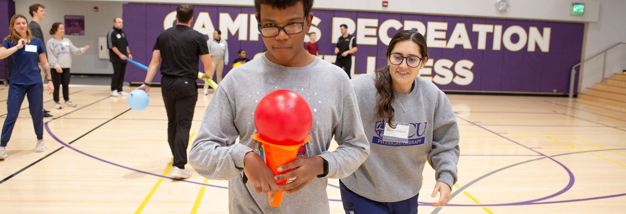 A physical therapy student encourages a HABIT camp participant during a race in the Health Sciences Student Center gym in December.