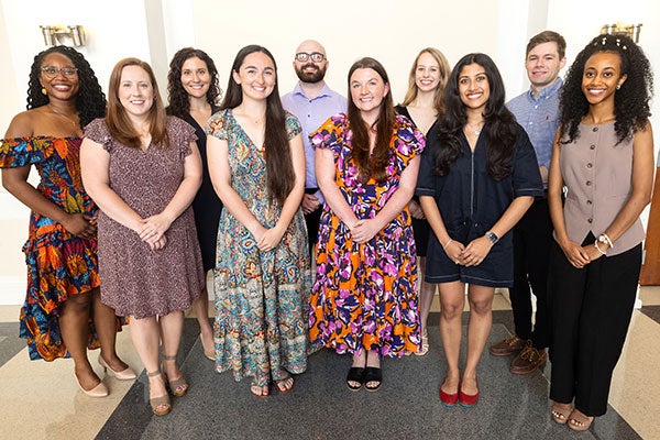 Two rows of ten young people in dresses and dress shirts stand in a group smiling for the camera.