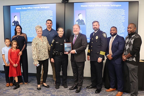 A group of people surround East Carolina University police officer Frannie Tarkington who is receiving the UNC System Officer of the Year award from system president Peter Hans.