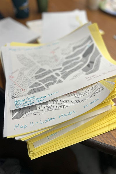 A stack of white and yellow papers show house lot locations and numbers.