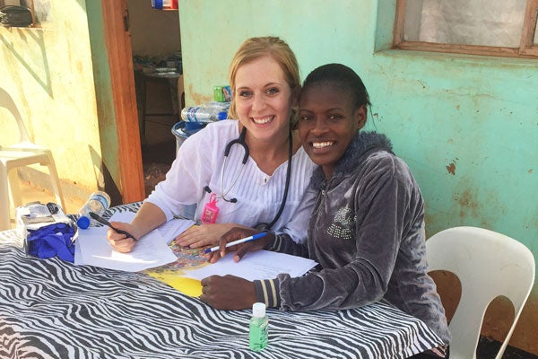 Two women smile as they sit at a table in an outdoor space in Zimbabwe.