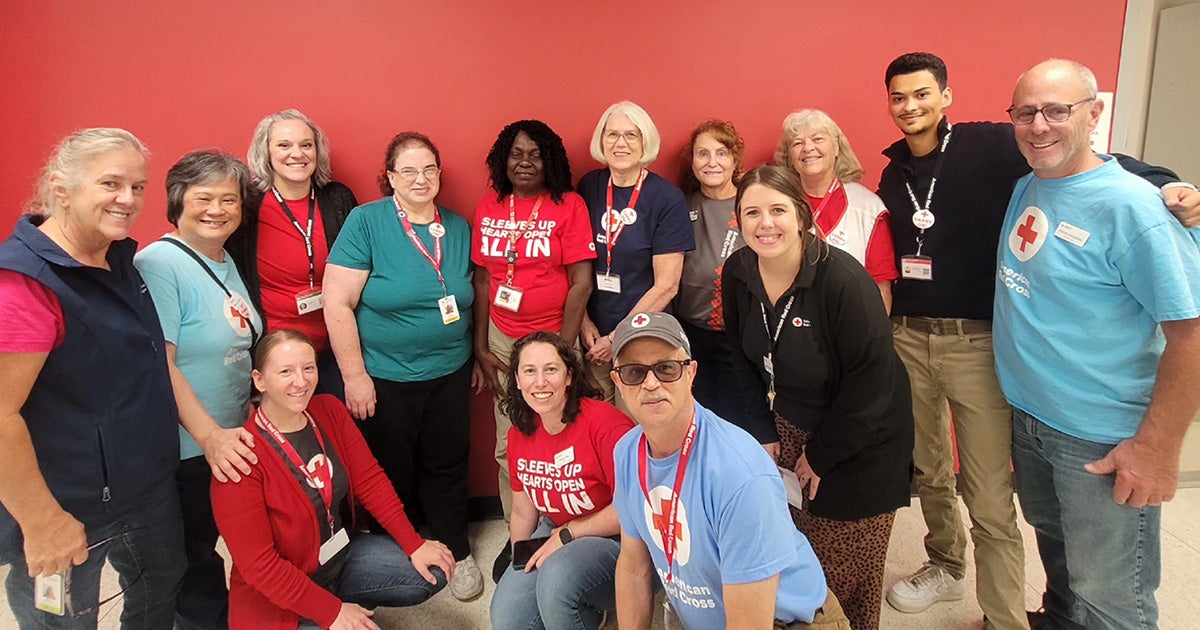 A group of people wearing Red Cross lanyards stands together while smiling.