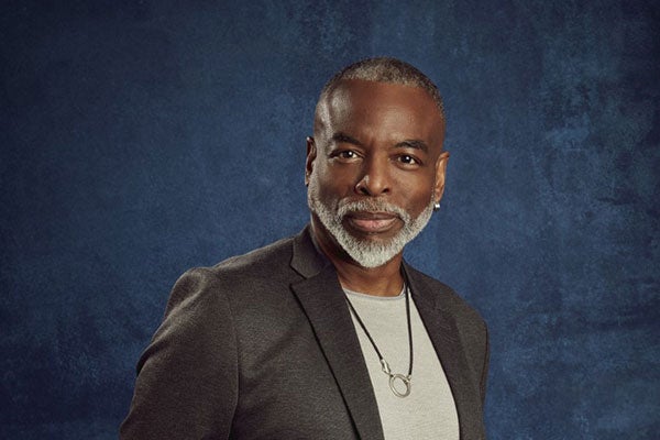 LeVar Burton poses for a headshot in a dark jacket with his hands in his pockets.