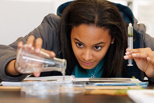A student in the biology lab measures and pours solutions to study the effects of photosynthesis in spinach leaves.