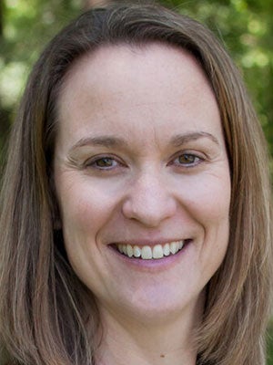 A woman with shoulder length brown hair smiles.