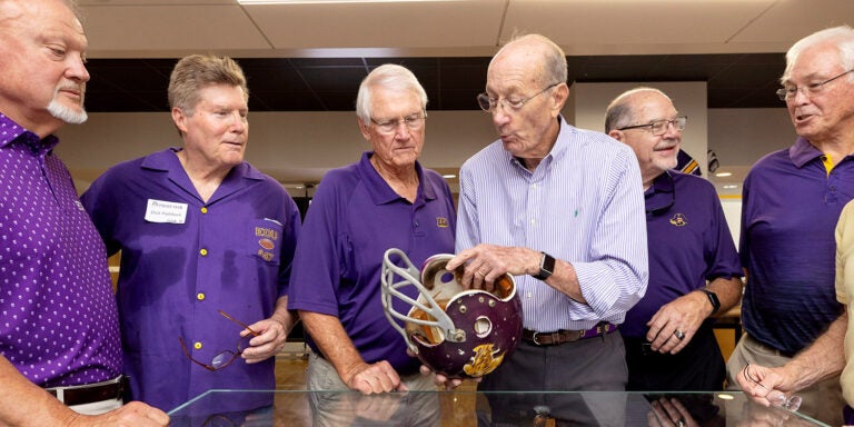 Grover Truslow talks to East Carolina University football teammates about the helmet he wore in the 1970 ECU-Marshall game. ECU and Marshall play this weekend at 4 p.m. at Dowdy-Ficklen Stadium.