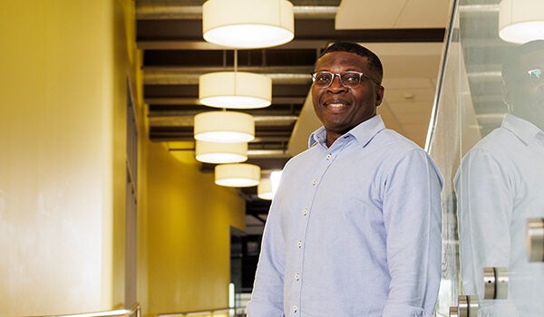 A man wearing glasses and a blue shirt smiles at the camera.