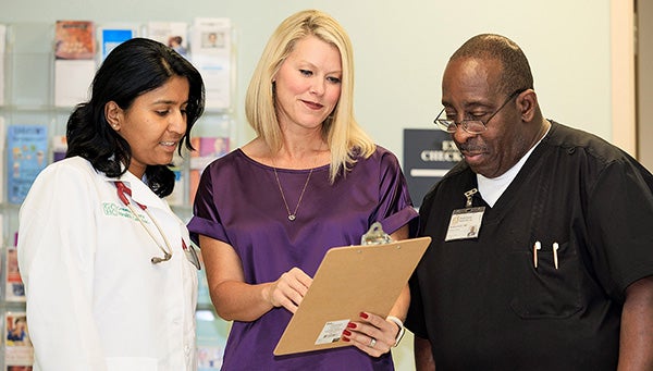 Angela Lamson looks at a chart with Greene County Health Care Dr. Sampoorna Velineni, left, and medical assistant Anthony Smith