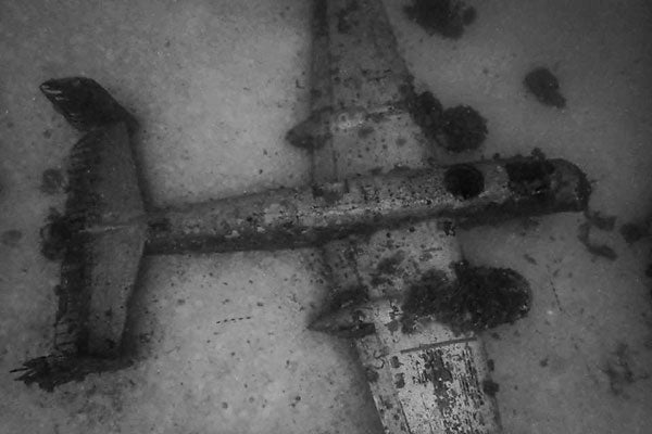 A black and white photograph of an aircraft on the sea floor.