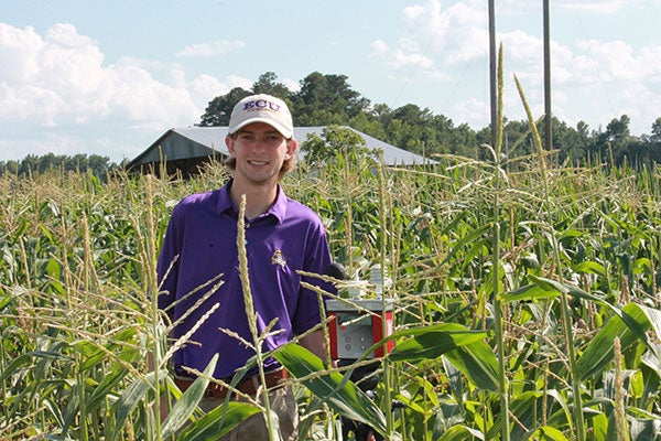 Ryan Edwards with a wet bulb globe device that measured atmospheric conditions in a field of corn