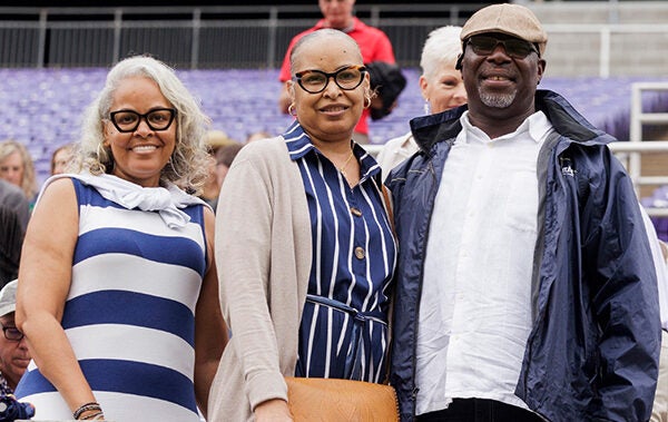 Two women and a man watch the graduation ceremony