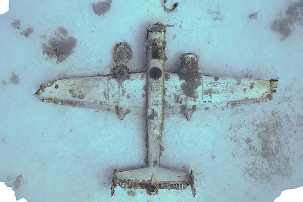 A colored, three-dimensional image of a military airplane sitting on its belly on the ocean floor.