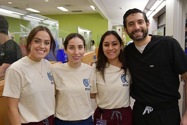 Two students and two faculty members pose in a row and smile for a photograph during the Feb. 15 Sonríe Clinic at the East Carolina University School of Dental Medicine. 