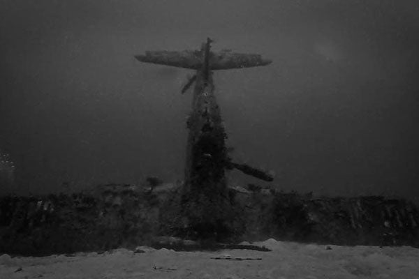 A black and white photograph shows an airplane standing on its nose on the sea floor.