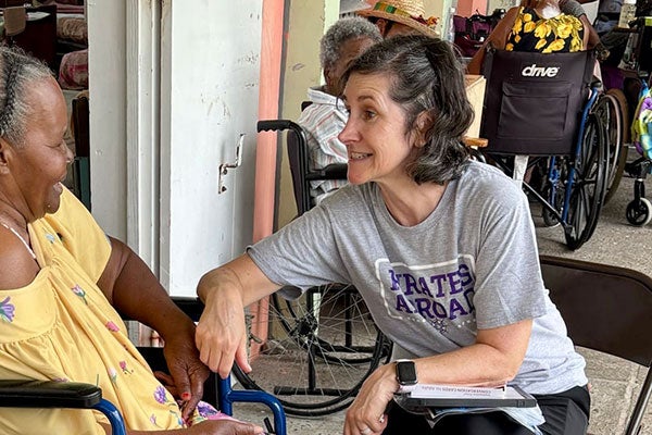 A woman in a grey shirt speaks to a woman in a yellow shirt.