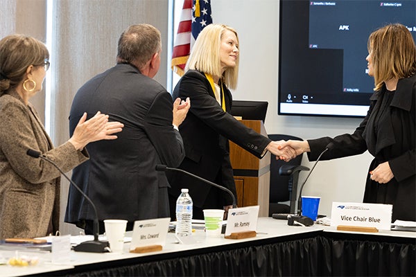 Women shaking hands at podium during award presentation.