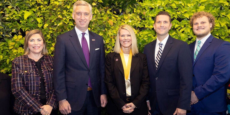 Group smiling together with foliage decoration in background.