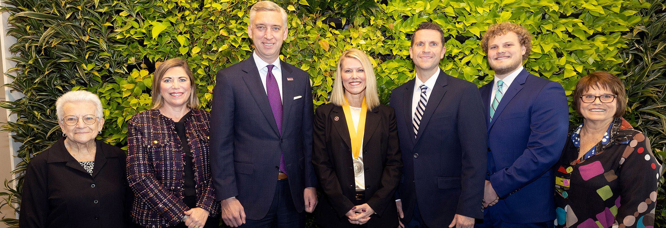 Group smiling together with foliage decoration in background.