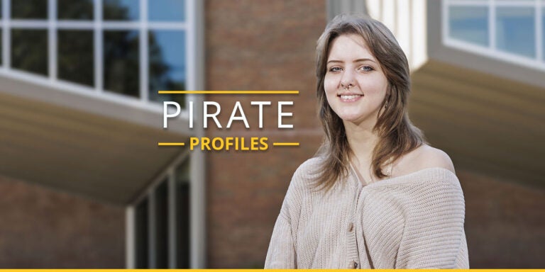 Senior Grace Scott smiles while standing in front of the Jenkins Fine Arts Center.