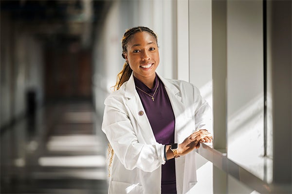 Dayana Allison poses in a long hallway on campus.