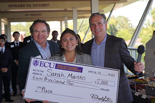 Sarah Maisto holds a big check. She’s flanked by Richard Twilley and John Chapman.