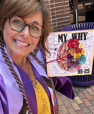 Woman wearing glasses and graduation regalia