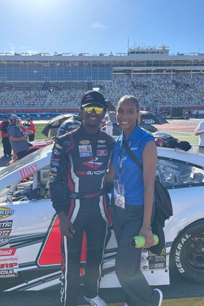 Nylah Alexander, a NASCAR Diversity Internship Program intern, stands with Rev Racing driver Lavar Scott prior to a race at Charlotte Motor Speedway. (Contributed photo)